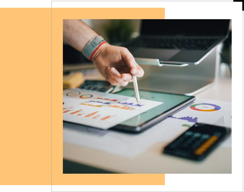 Hand pointing to printed revenue charts beside a laptop