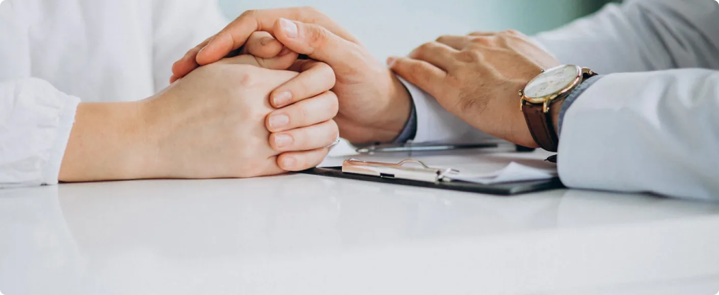 Clinician and patient with hands resting on a desk during a consultation